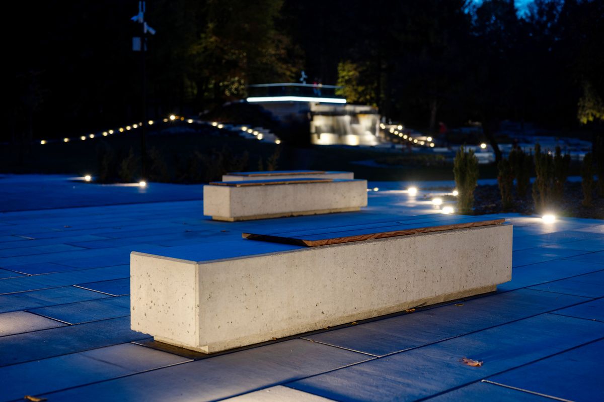 Podświetlone ławki betonowe w nocy na betonowej posadzce w parku.