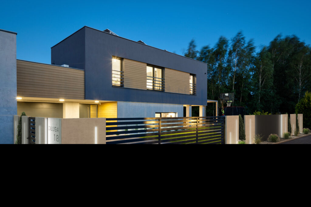 Nocny widok na dom z nowoczesnym ogrodzeniem betonowym