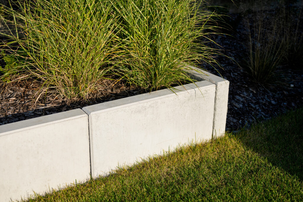 Szary betonowy murek oporowy w nowoczesnym ogrodzie.