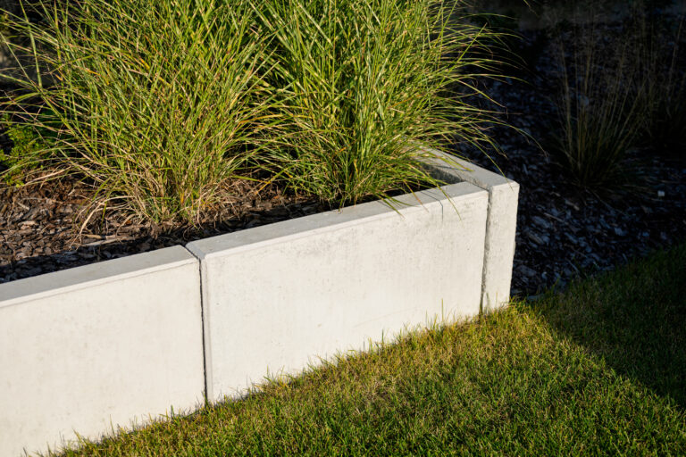 Szary betonowy murek oporowy w nowoczesnym ogrodzie.